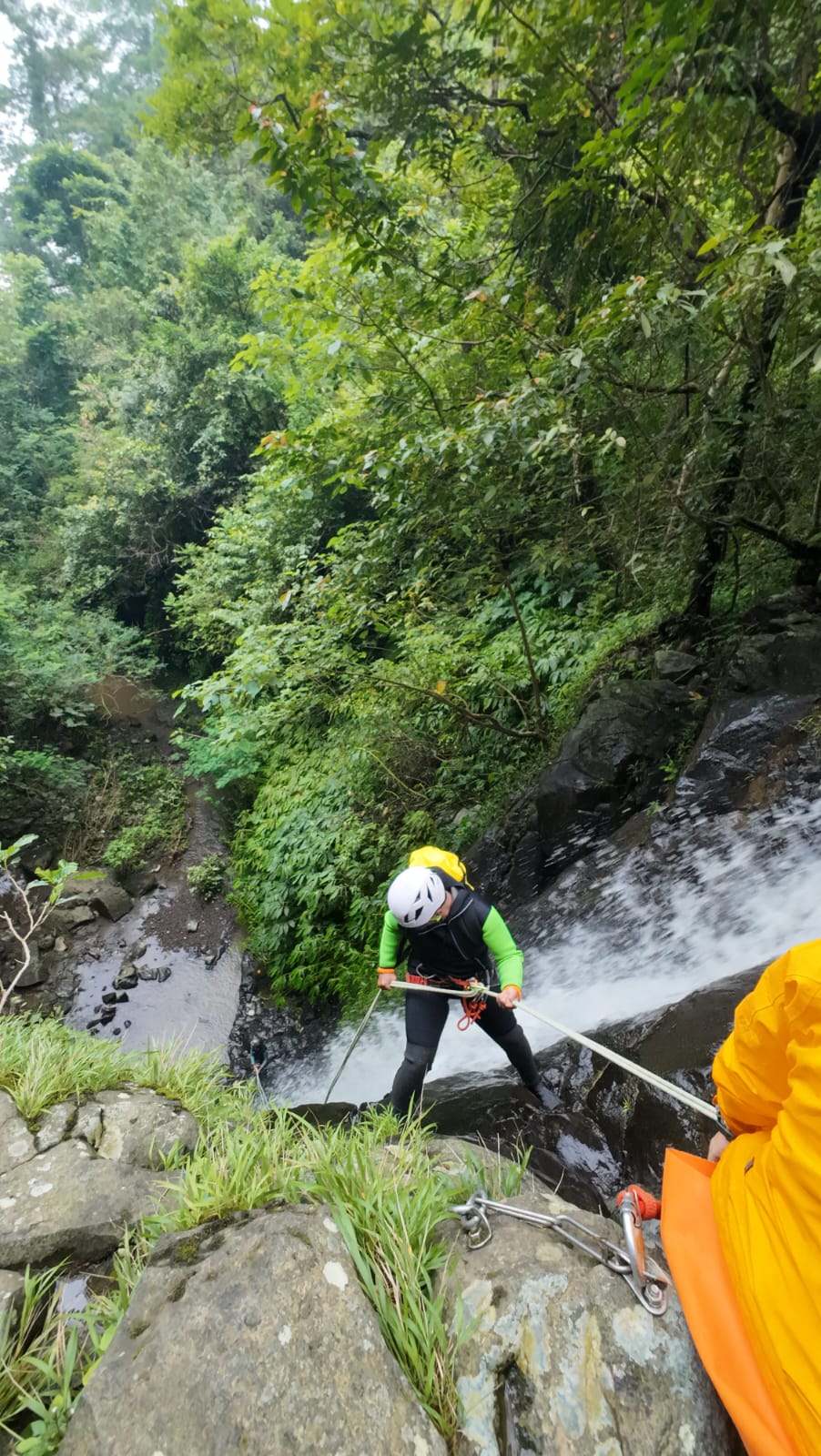 Canyoning Bali participant rappelling a 35-meter waterfall in Samba Canyon surrounded by tropical rainforest and dramatic canyon scenery.